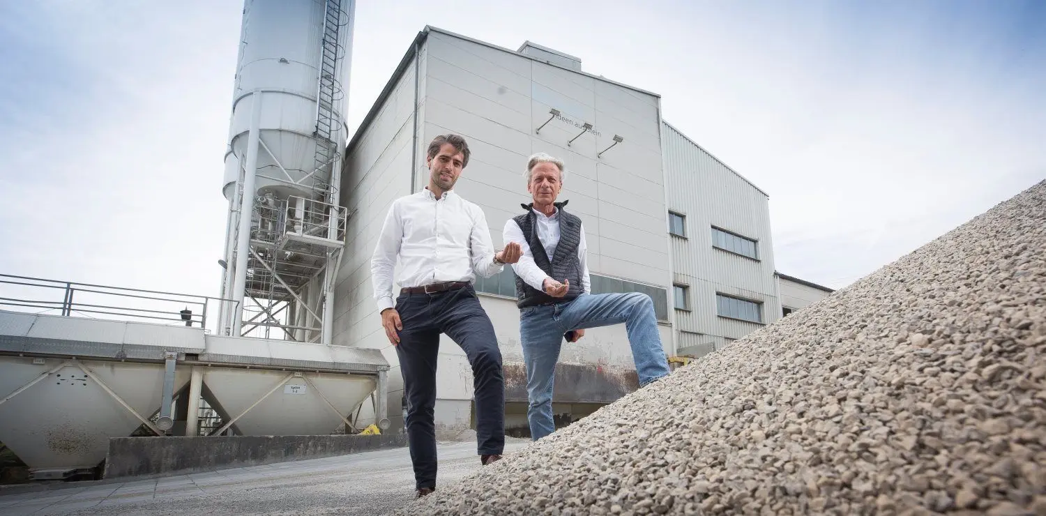 Durch die Finger von Felix Braun (links) und Wilfried Braun, beide Geschäftsführer, rieselt Betonstein-Ausschuss, der auf dem eigenen Betriebsgelände gebrochen wurde. Daraus stellen sie Recyclingbeton her. ⇥