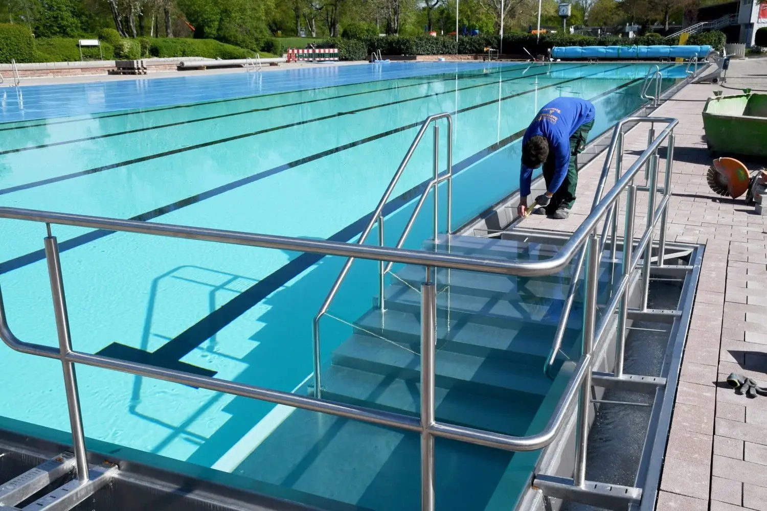 Das Schwimmerbecken im Wellenfreibad Markwasen hat einen Komforteinstieg (links unten) erhalten. Ein Arbeiter legt letzte Hand an der neuen Beckenumrandung aus Edelstahl an.