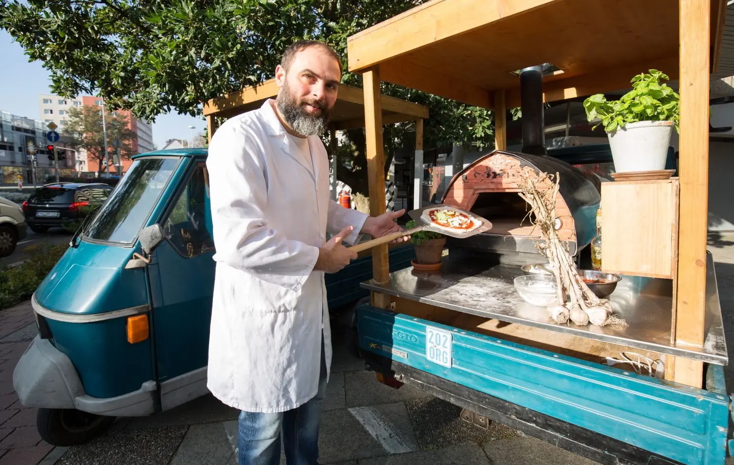 Francesco Contino schiebt die Pizza in den Steinofen. Hinter ihm steht noch die Ape fürs neapolitanische Catering.⇥