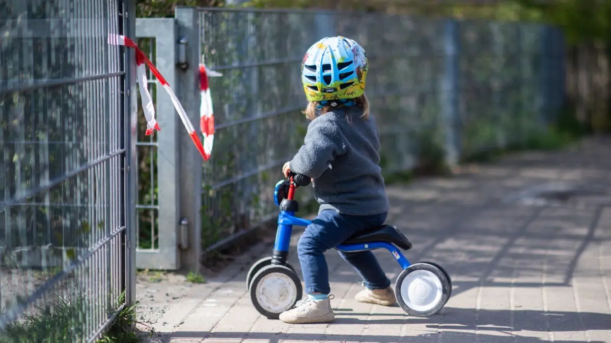 Ein Kind vor einem Absperrband. Für viele Familien sind Kitas noch immer tabu. Dagegen regt sich mehr und mehr Widerstand.
ARCHIV - 16.04.2020, Niedersachsen, Hannover: Frida steht vor einem abgesperrten Spielplatz. Seit Wochen sind die Kitas in Deutschland geschlossen, ein Ende ist nicht in Sicht. Insbesondere für Eltern, deren Kind keinen Anspruch auf Notbetreuung hat, sind die strengen Vorgaben belastend. (zu dpa "Private Spielgruppen oder doch zu Oma? Kinderbetreuung ohne Kita") Foto: Julian Stratenschulte/dpa +++ dpa-Bildfunk +++