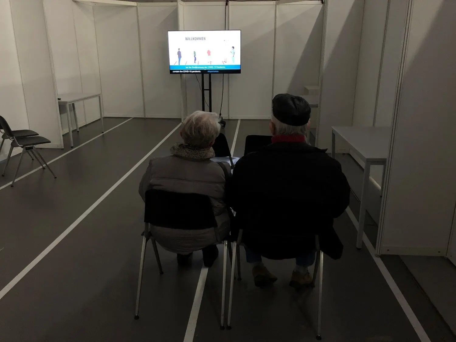 Die beiden Senioren beim Info-Film vor ihrer 1. Impfung im Zentralen Impfzentrum in der Tübinger Paul-Horn-Arena.⇥