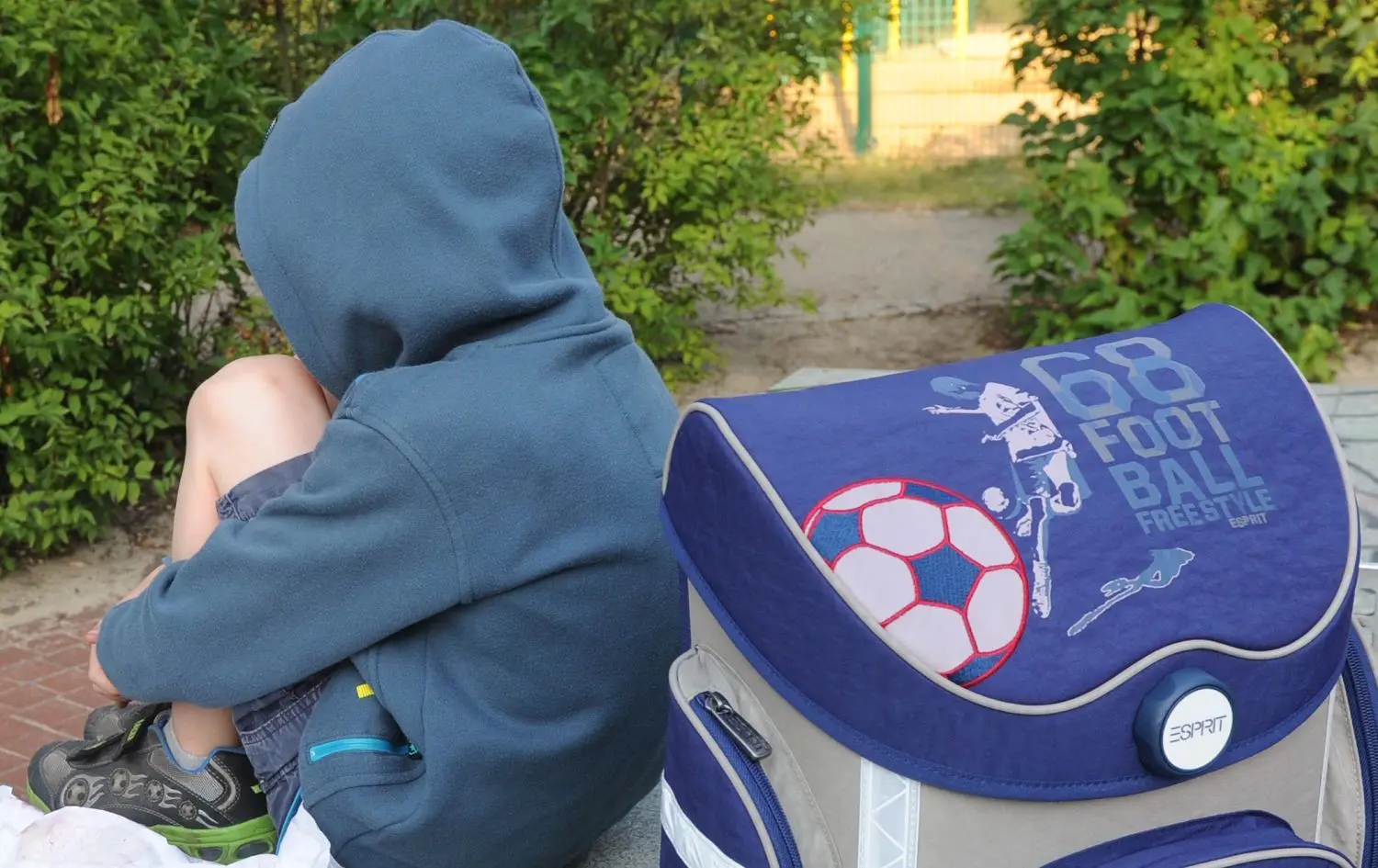 Ein Kind kapselt sich ab: Der Junge sitzt mit seinem Schulranzen auf einer Tischtennisplatte (Symbolfoto).