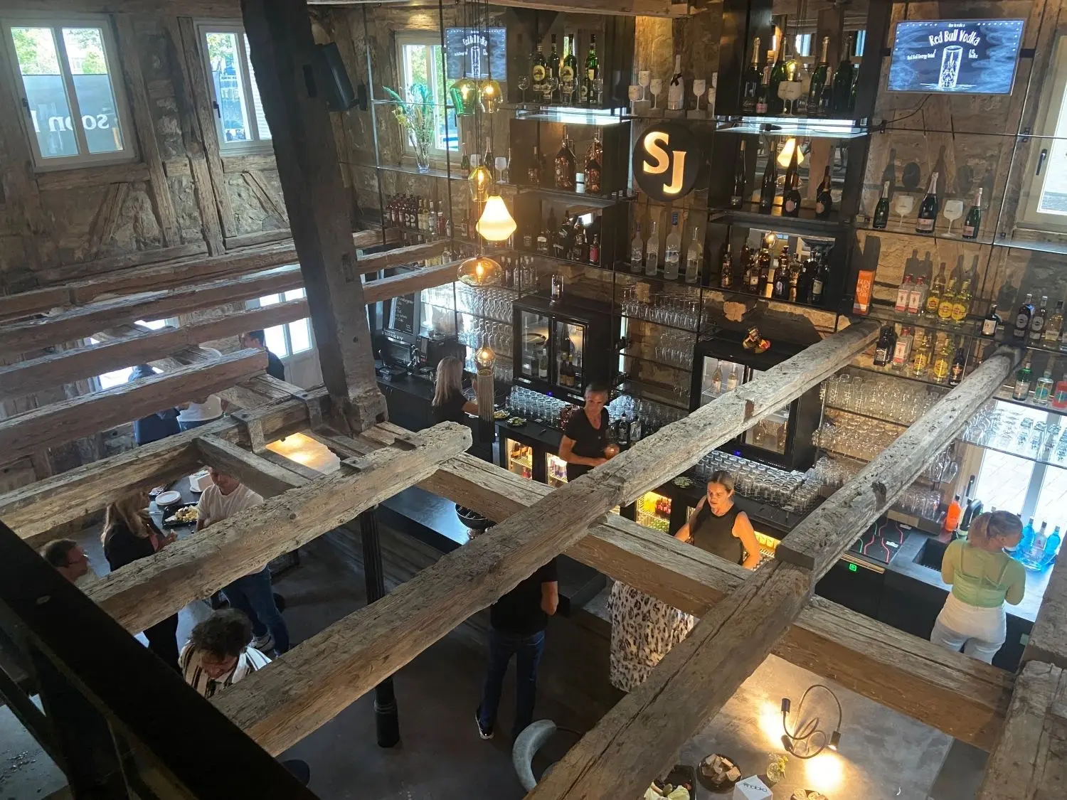 Der Gastraum der neuen Göppinger Bar „Son of John“ ist so hoch wie das gesamte zwei- bis dreistöckige Gebäude und wirkt optisch vor allem durch das freiliegende Originalgebälk, das den Blick freigibt auf die Bar mit dem großen „SJ“-Emblem. ⇥
