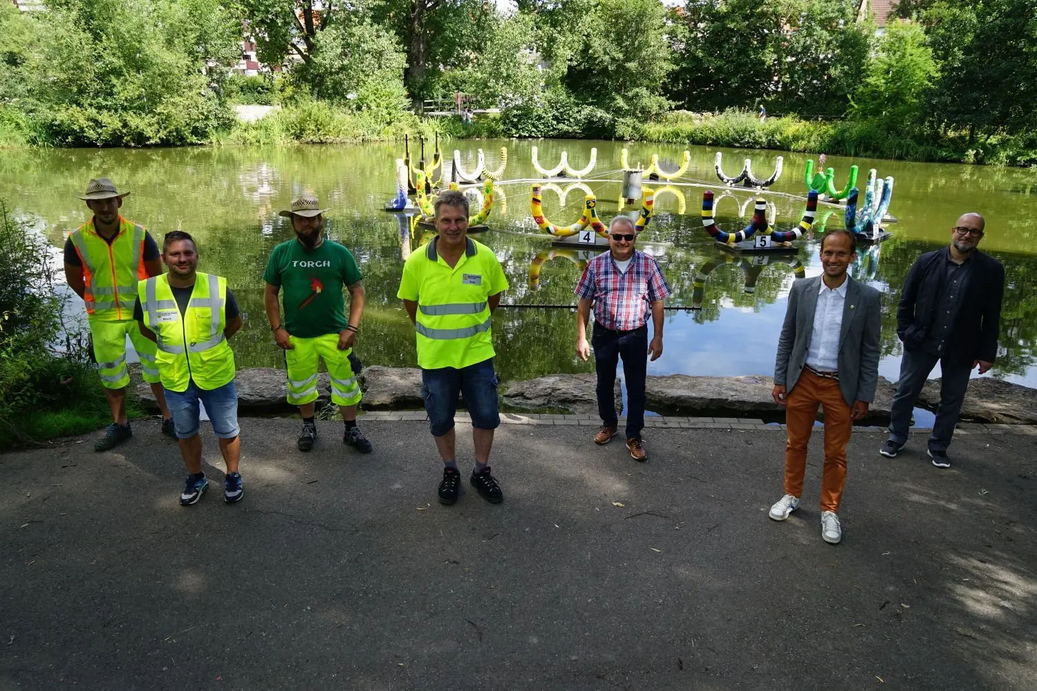 Horst Herold, Oberbürgermeister Dr. Christoph Grimmer und Johannes Köder (von rechts) mit Mitarbeitern des Baubetriebshofes beim Start des Wettbewerbs. Auf dem Gewässer schwimmt das Horaffen-Karussell.⇥