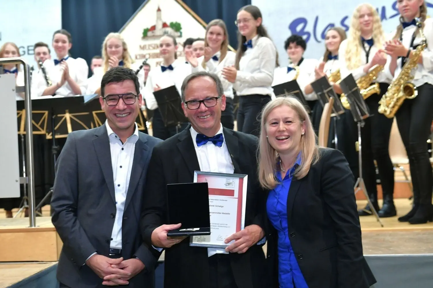 Marek Scheliga wurde für sein Engagement mit der Erich-Ganzenmüller-Medaille gewürdigt. Auf dem Foto mit Matthias Dolpp, Vorsitzender des Kreisblasmusikverbands (links), und Claudia Ströhm vom Präsidium des Landesverbandes.⇥