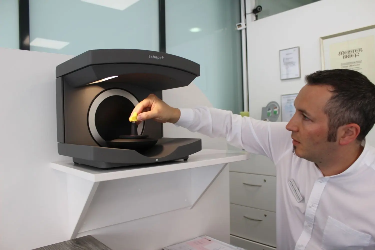 Im Mittelpunkt des Produktionsprozesses steht der digitale Scanner, in den Philipp Offenbecher die  vorher mit der Hand erstellte Abformung des Gehörgangs einsetzt.⇥