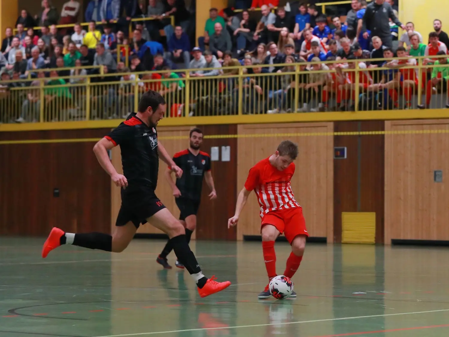 Ein Hessentaler Angreifer (rot) wird von zwei Spielern des SV Gailenkirchen verfolgt. Die Stadtmeisterschaft in der Hagenbachhalle genießt hohes Prestige unter den Haller Vereinen, was die engagiert geführten Duelle verdeutlicht haben.⇥
