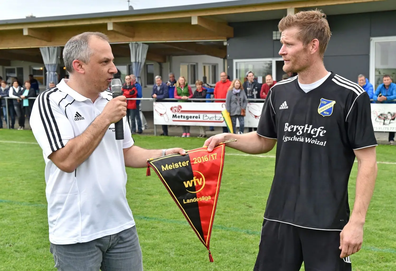 Landesliga-Staffelleiter Andreas Schele (links) überreicht SSV-Kapitän Christian Endler den Meisterwimpel.