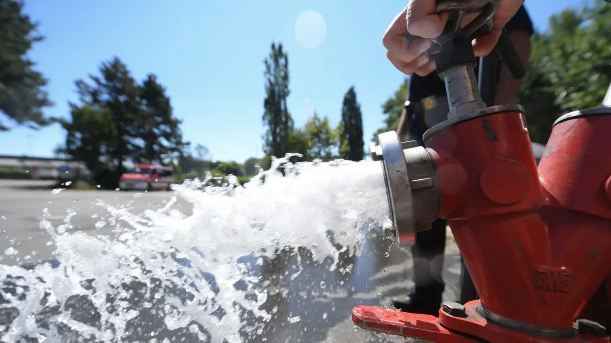 Wasser sprudelt mit hohem Druck aus einem Hydranten. Aber was, wenn nicht?
06.08.2018, Hessen, Kelkheim-Ruppertshain: Jan Herbert von der Freiwilligen Feuerwehr dreht beim Einrichten einer Notleitung zur Trinkwasserversorgung des Ortes einen Hydranten auf. In den Kelkheimer Stadtteilen Ruppertshain und Eppenhain (Main-Taunus-Kreis) ist das Trinkwasser knapp geworden. Betroffen sind rund 3500 Einwohner. Foto: Arne Dedert/dpa +++ dpa-Bildfunk +++