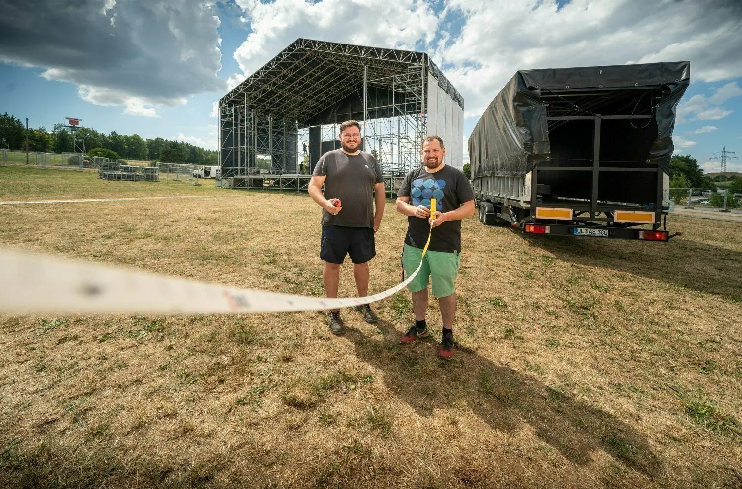 Clemens Wieser (links) und Michael Gugelfuß vom Obstwiesenfestival nehmen Maß für die neue dritte Bühne, die rechts auf dem Lkw-Anhänger schon bereit steht. Ab Donnerstag gibt es Programm auf dem Gelände.⇥