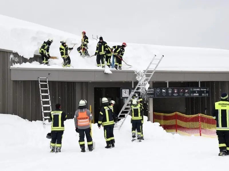 Feuerwehrleute räumen Schnee vom Dach einer Ski-Liftstation in Bayern. Foto: Tobias Hase
