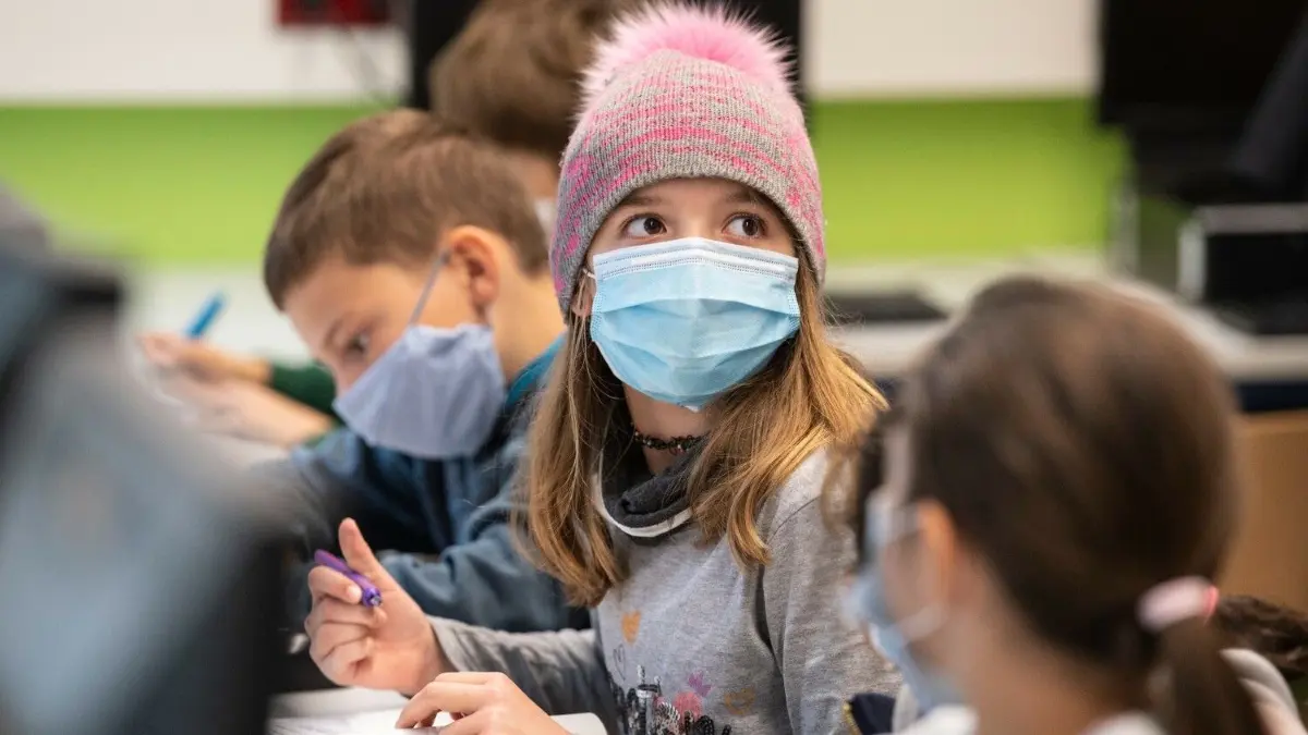 Werden in den Schulen Masken und Tests wieder Pflicht? Und brauchen Kinder künftig eine Gesundschreibung nach Corona-Verdacht? (Symbolbild)
Mit Mundschutzmasken sitzen Schülerinnen und Schüler der fünften Klasse eines Gymnasiums in Frankfurt im Unterricht, ein Mädchen trägt eine Mütze. Neben dem obligatorischen Tragen von Masken gehört das regelmässige Lüften der Klassenräume zum Hygienekonzept an den hessischen Schulen. +++ dpa-Bildfunk +++