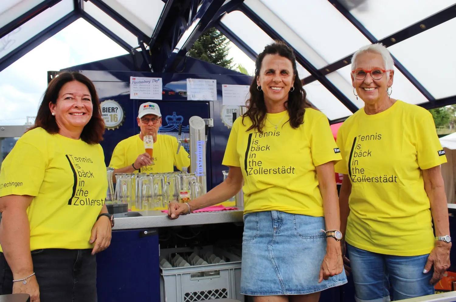 Alle in leuchtendem Gelb und mit der Botschaft „Tennis is bäck in the Zollerstädt“: die ehrenamtlichen Helferinnen und Helfer vom Tennisclub Hechingen. Am Bierbrunnen von links: Lilly Guster, Jürgen Merkel, Susi Guster und Moni Guster.