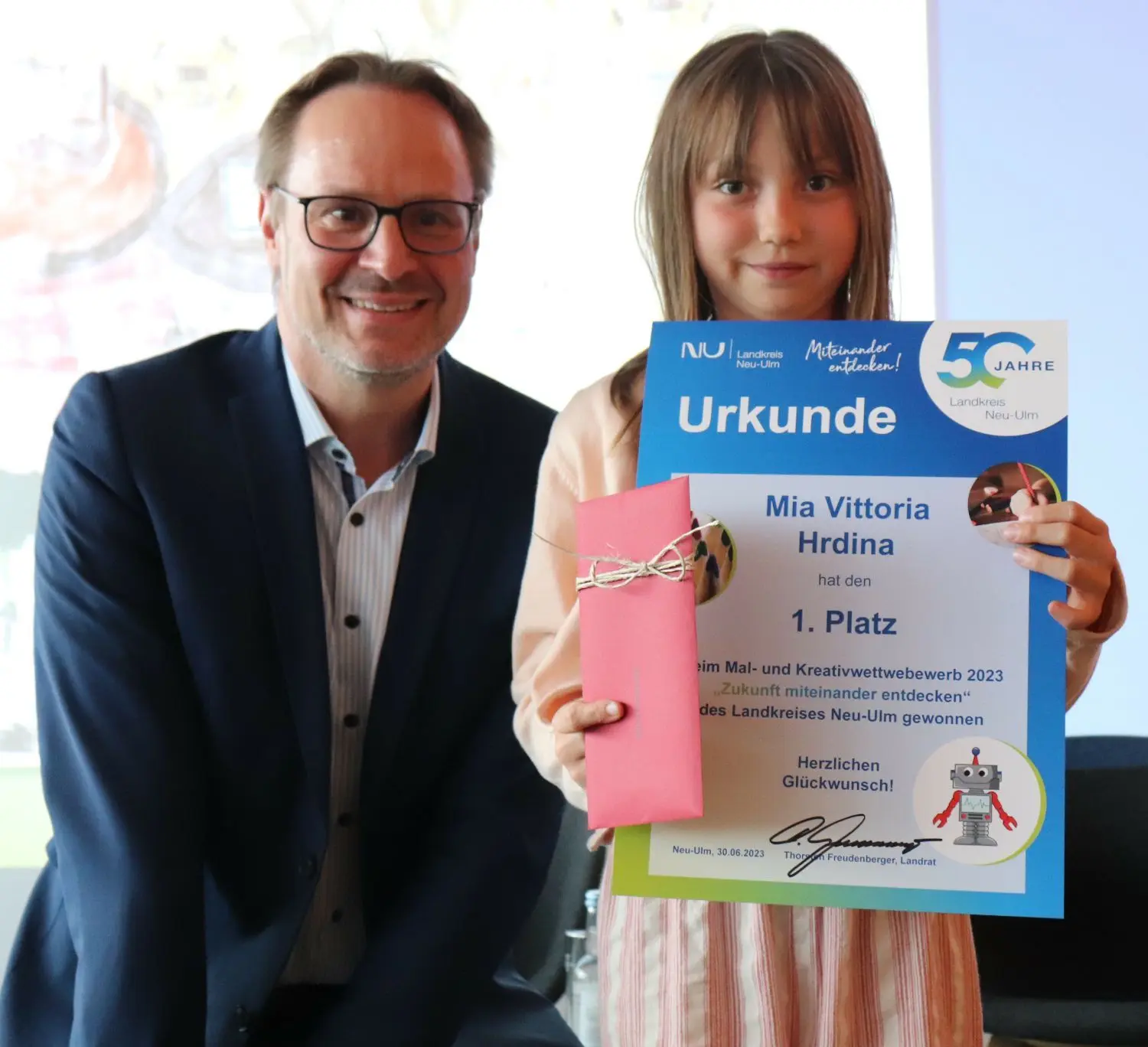 Zukunftstag im Landkreis Neu-Ulm: Prämierung von Mia Vittoria Hrdina beim Malwettbewerb zum Landkreisjubiläum mit Landrat Thorsten Freudenberger.⇥
