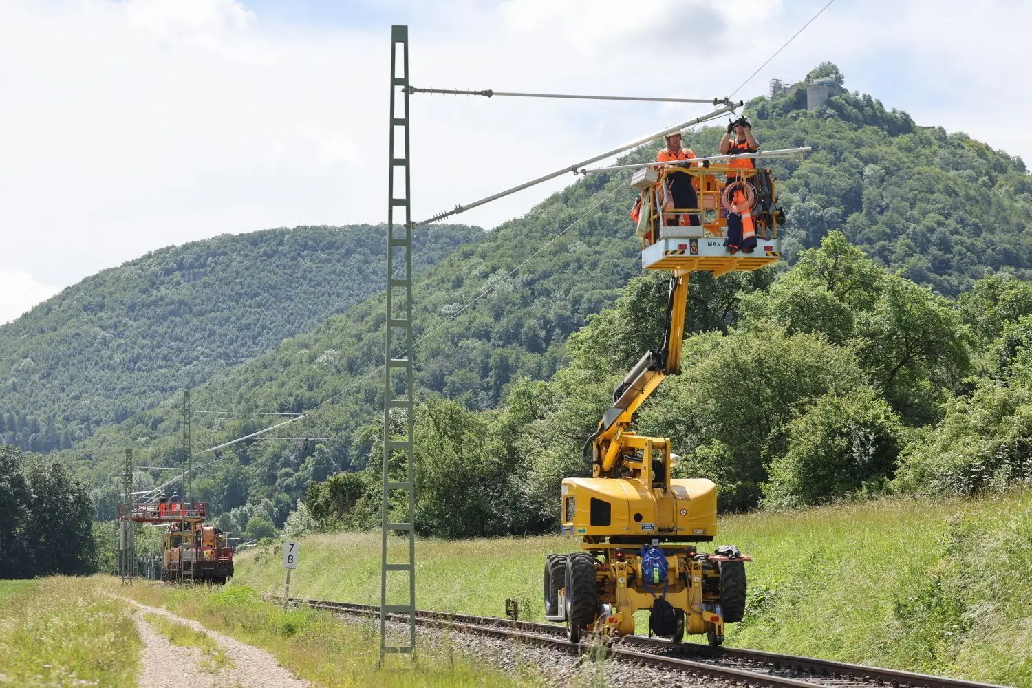 Ein Motorturmwagen ist zwischen Dettingen und Bad Urach unterwegs, um das Oberleitungssystem zu installieren. ⇥