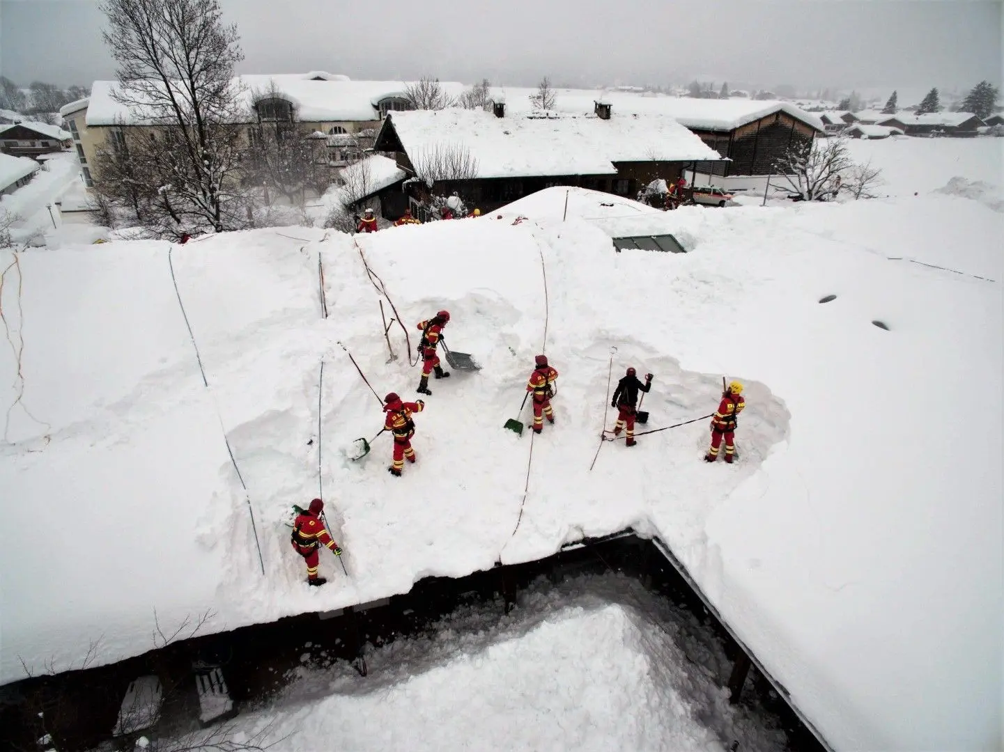 Weiße, nasse Last auf den Dächern: DLRG-Helfer räumen Schneemassen von einem Haus im bayerischen Schleching.⇥