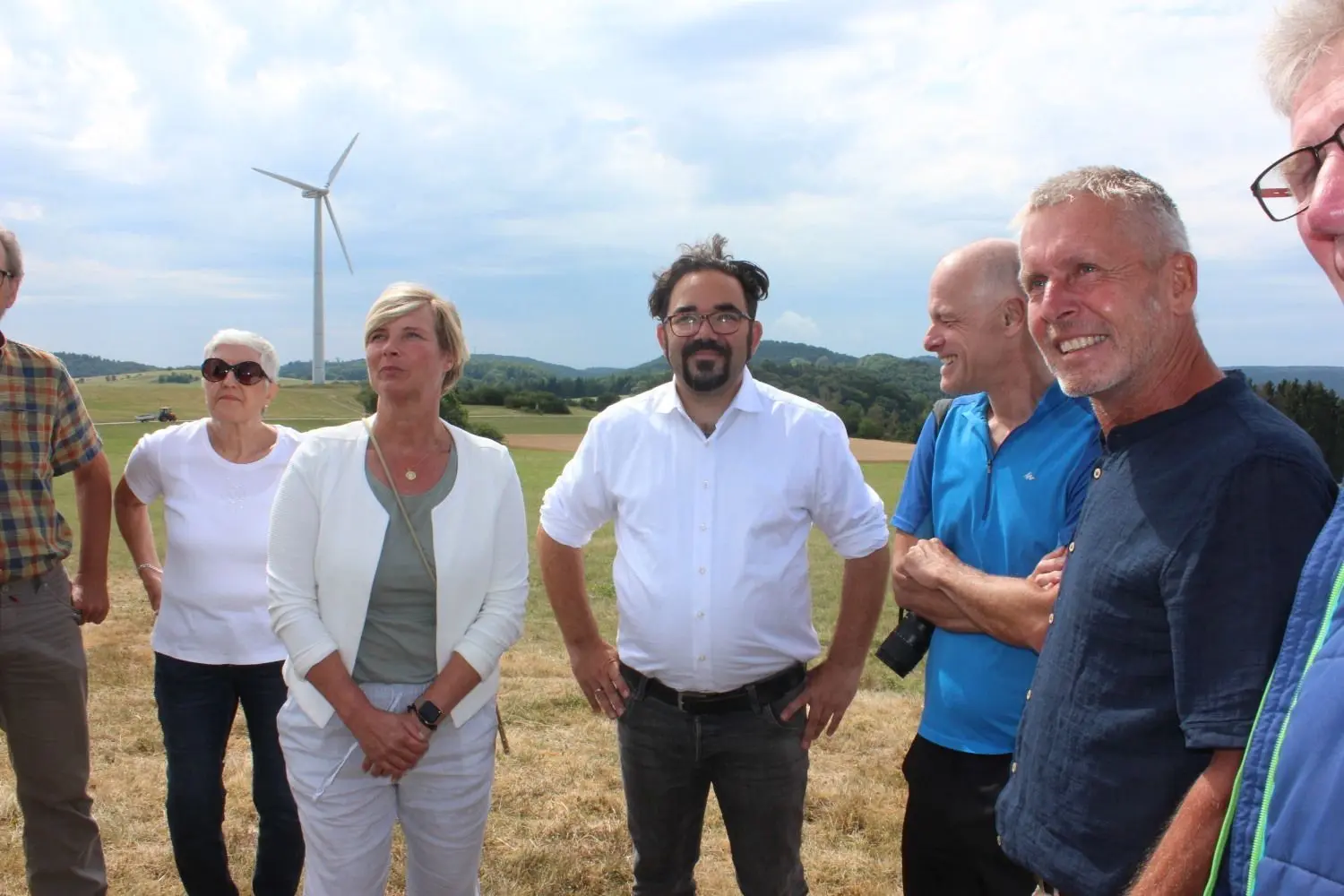 Drei Windräder drehen sich auf dem Melchinger Himmelberg, eins davon ist im Hintergrund zu sehen. Mit auf dem Foto: Bundestagsabgeordneter Chris Kühn (3. v. r.), die Landtagsabgeordnete Cindy Holmberg (2. v. l.) und Sowitec-Geschäftsführer Frank Hummel (r.). ⇥