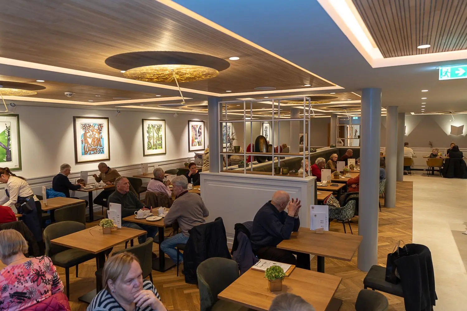 Modernes Design, bequeme Sitzmöbel und der offene Blick bis in die Küche – das Café Sommer hat sich bei seinem Umbau neu erfunden. An den Wänden sind Bilder des Eninger Künstlers HAP Grieshaber ausgestellt. ⇥