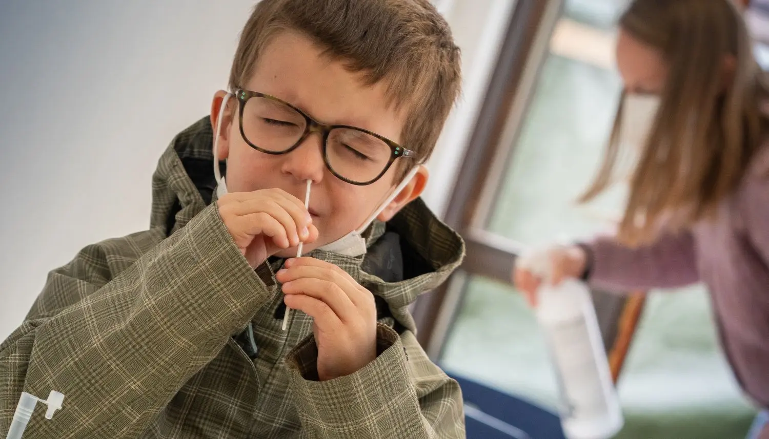 Tapfer und ohne Probleme macht Erstklässler Cornelius am Montag einen Selbsttest. In der Meinloh-Grundschule gibt es für Kinder aktuell nur eine Notbetreuung. Hinter ihm wird der Platz im Test-Bereich für das nächste Kind desinfiziert.⇥