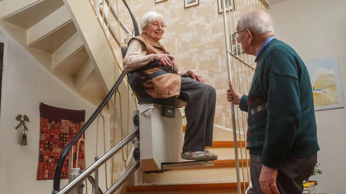 Ältere Dame sitzt auf einem Treppenlift und ihr Mann steht am Geländer Download am 7.9.2023 für Wirtschaft Foto: © Ingo Bartussek/adobe.stock.com