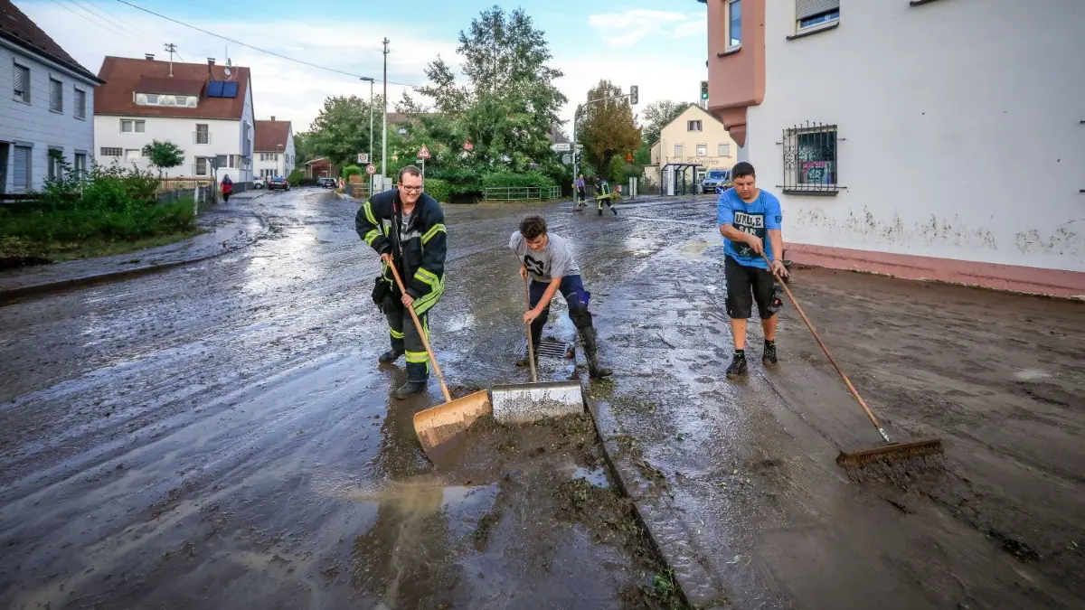 Mit vereinten Kräften: Anwohner und Feuerwehrleute beseitigen mit Schaufeln und Besen die Spuren des Unwetters.
Hochwasser in Ulm Einsingen