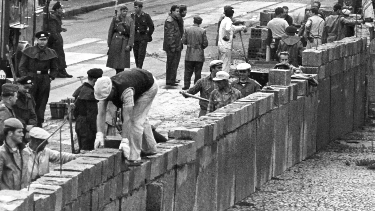 Mauerbau in Berlin: ARCHIV - 18.08.1961, DDR, Berlin: Unter der Aufsicht von bewaffneten Volkspolizisten errichtet eine Ostberliner Maurerkolonne am an der sowjetisch-amerikanischen Sektorengenze am Potsdamer Platz eine Mauer. (zu "Baubeginn der Berliner Mauer vor 59 Jahren") (zu dpa: «Archivbestände aus der DDR sind oft kaum zu nutzen») Foto: UPI/UPI/dpa +++ dpa-Bildfunk +++