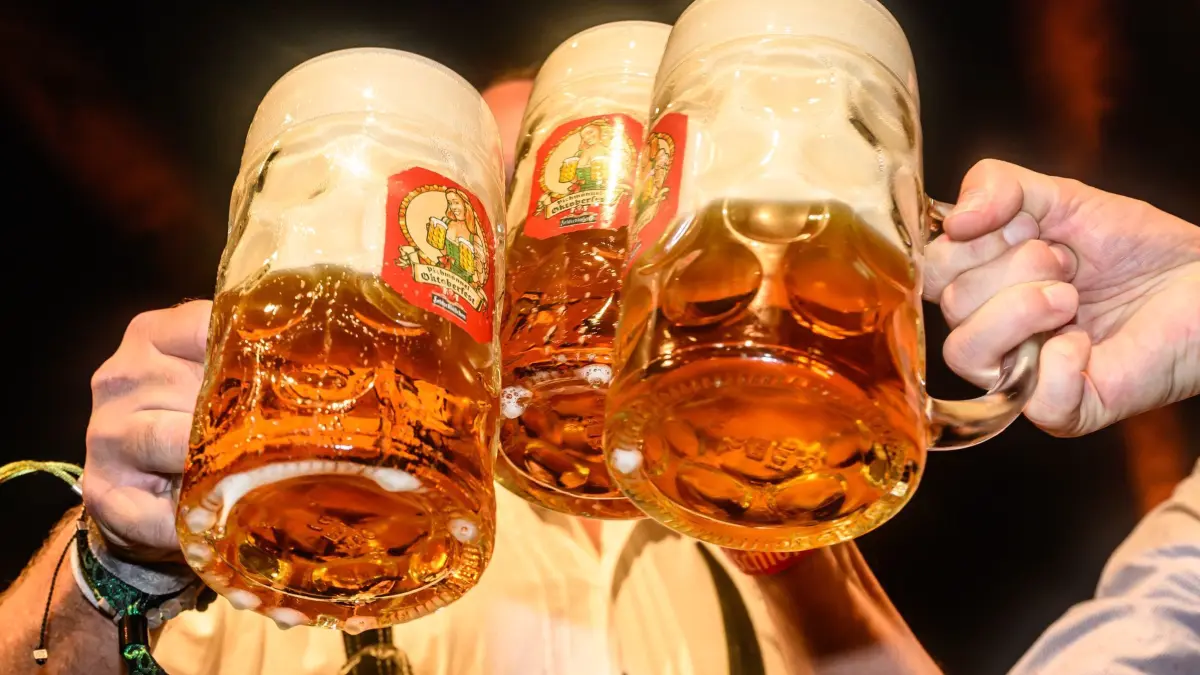 Bier: ARCHIV - 21.09.2023, Sachsen, Dresden: Mit Maßkrügen wird am traditionellen Fassbieranstich zum Dresdner Oktoberfest angestoßen. Die sächsischen Brauer leiden nach eigener Einschätzung unter stark gestiegenen Kosten und einer angespannten Lage in der Gastronomie. (zu dpa: «Bierabsatz in Sachsen rückläufig - Branche für 2024 zuversichtlich») Foto: Robert Michael/dpa +++ dpa-Bildfunk +++