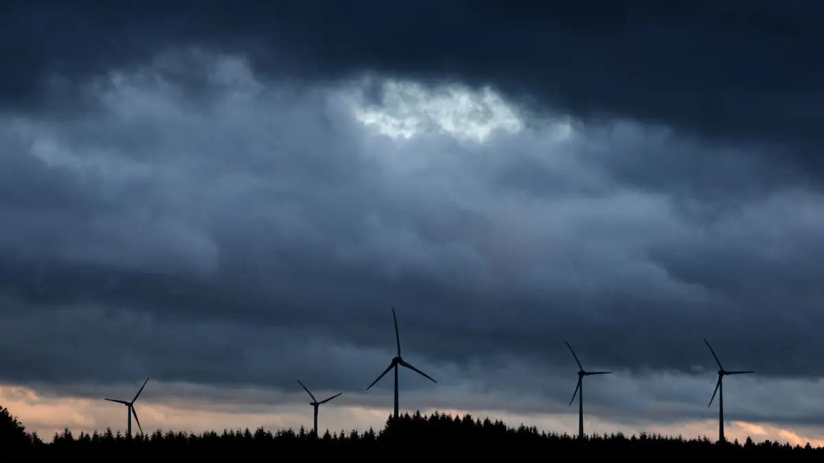 Windräder in Bayern: ARCHIV - 01.08.2023, Bayern, Aitrang: Windräder stehen bei Aitrang im Allgäu unter dichten Regenwolken hinter einem Wald. (zu dpa: «Mehr Abstand zu Rotoren: Gelingt Kompromiss für Windpark in Altötting?») Foto: Karl-Josef Hildenbrand/dpa +++ dpa-Bildfunk +++