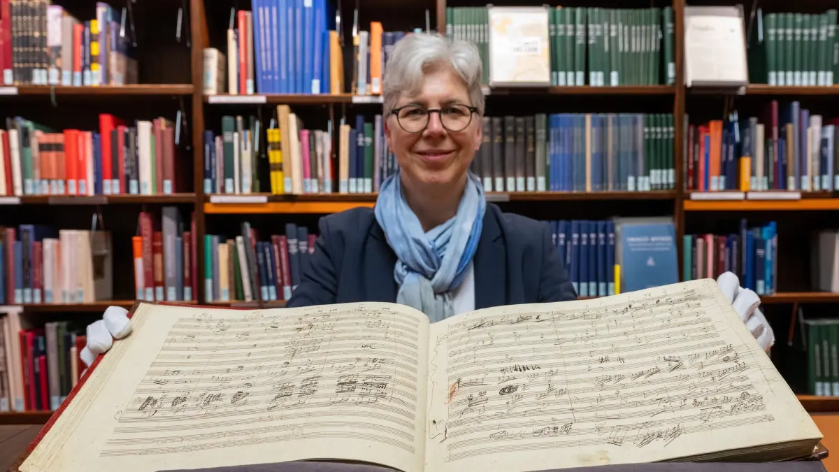 Autograph der 9. Sinfonie von Beethoven: PRODUKTION - 10.04.2024, Berlin: Martina Rebmann, Leiterin der Musikabteilung mit Mendelssohn-Archiv in der Staatsbibliothek zu Berlin, hält die aufgeschlagene „Handschrift der Sinfonie Nr. 9 des Komponisten L. van Beethoven“ in den Händen. Die Uraufführung der Sinfonie fand am 07. Mai 1824 in Wien statt. Die beschriebenen Notenblätter wurden um 1850 gebunden. (zu dpa: «Staatsbibliothek zeigt Originalpartitur von Beethovens Neunter») Foto: Soeren Stache/dpa +++ dpa-Bildfunk +++