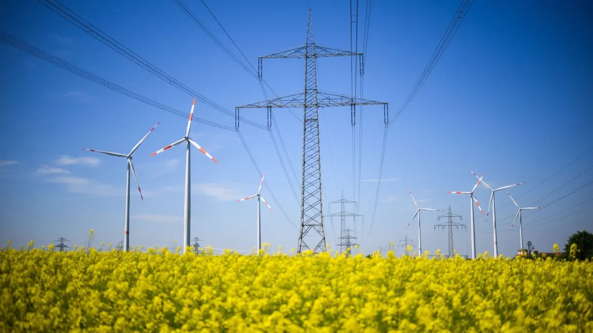 Energiewende in Niedersachsen: 02.05.2024, Niedersachsen, Hohenhameln: Windräder und eine Hochspannungsleitung stehen hinter einem Rapsfeld im Landkreis Peine. Am Donnerstag findet ein Plenum zur Task-Force «Energiewende» mit der niedersächsischen Landesregierung statt. Foto: Julian Stratenschulte/dpa +++ dpa-Bildfunk +++