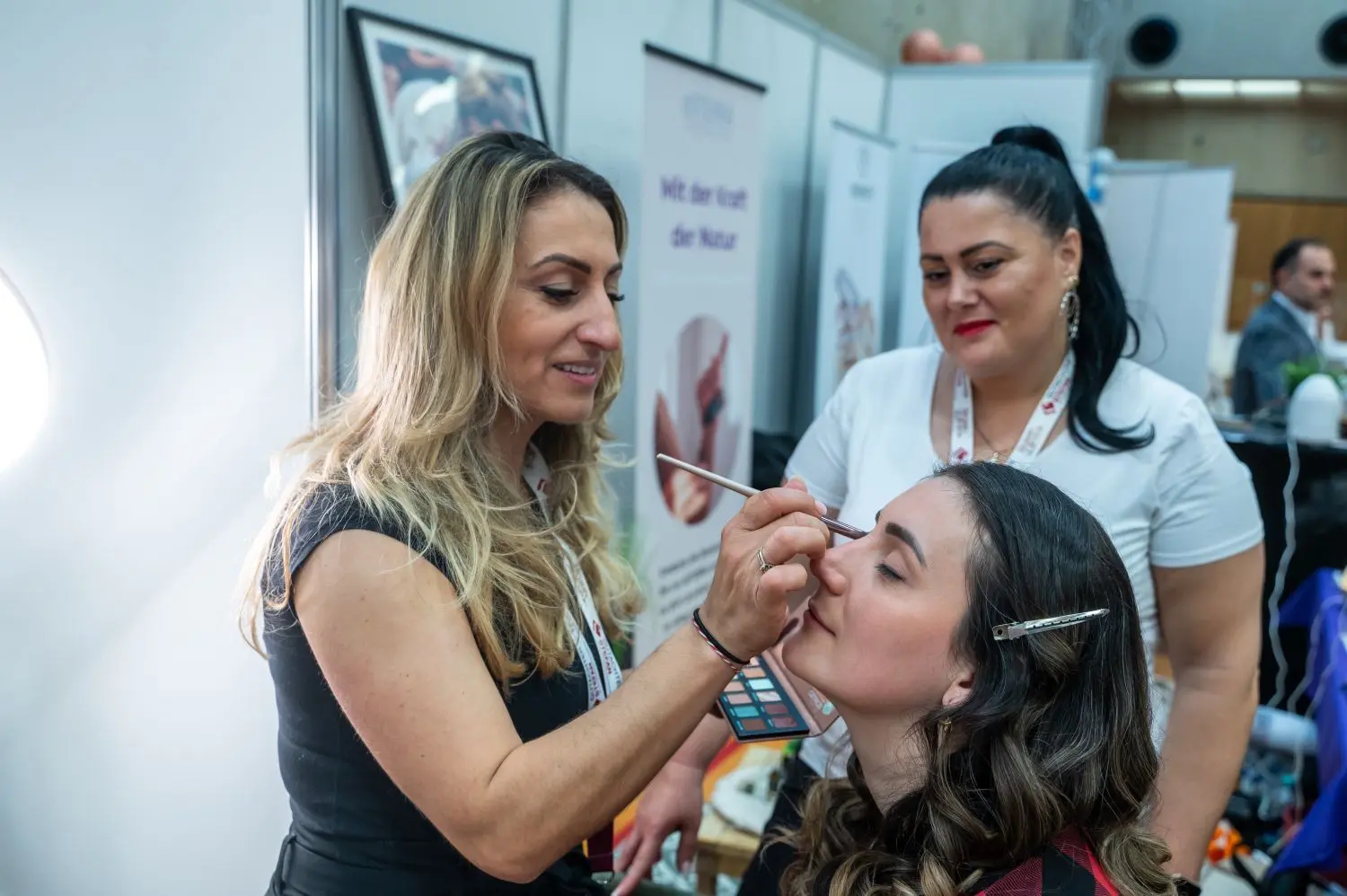 Eine Kosmetikerin trägt bei einer Frau Make-up auf.