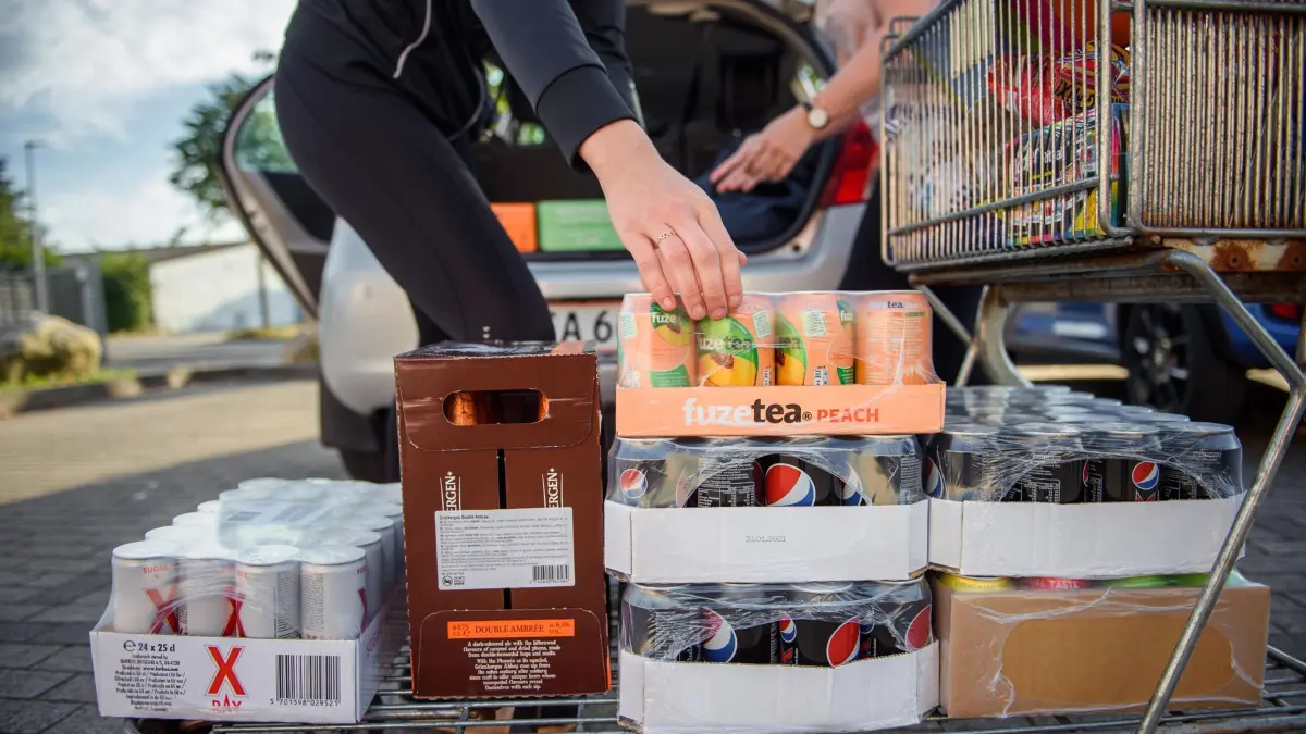 Pfandfreie Dosen an der deutsch–dänischen Grenze: ARCHIV - 20.08.2020, Schleswig-Holstein, Flensburg: Zwei Däninnen laden Paletten voller pfandfreier Getränkedosen auf einem Parkplatz vor einem Supermarkt in Flensburg an der deutsch-dänischen-Grenze in ihr Auto. (zu dpa: «EU-Verpackungsverordnung - Deutsch-dänisches Grenzland ist alarmiert») Foto: Gregor Fischer/dpa +++ dpa-Bildfunk +++