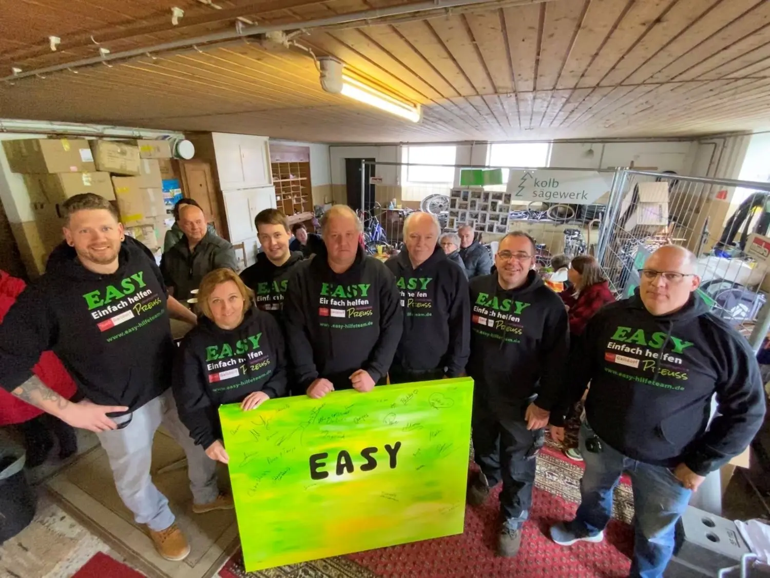 Die Gaildorfer Hilfsgruppe „Easy“ freut sich über die vielen Gäste, die zum Jubiläum gratulieren. Sie alle können auf einer Leinwand im „Easy-Grün“ unterschreiben. Von rechts: Michael Alkan, Heiko Schmidt, Christian Kandzia, Torsten Reupke sowie Darius und Andrea Dirksmann. Patrick Preuss (links außen) vom gleichnamigen Hüpfburgen-Verleihservice, spendete neue Pullover. Auf dem Foto fehlen Janina Bohn, Nick Barth und Matthias Wiedenmann.⇥