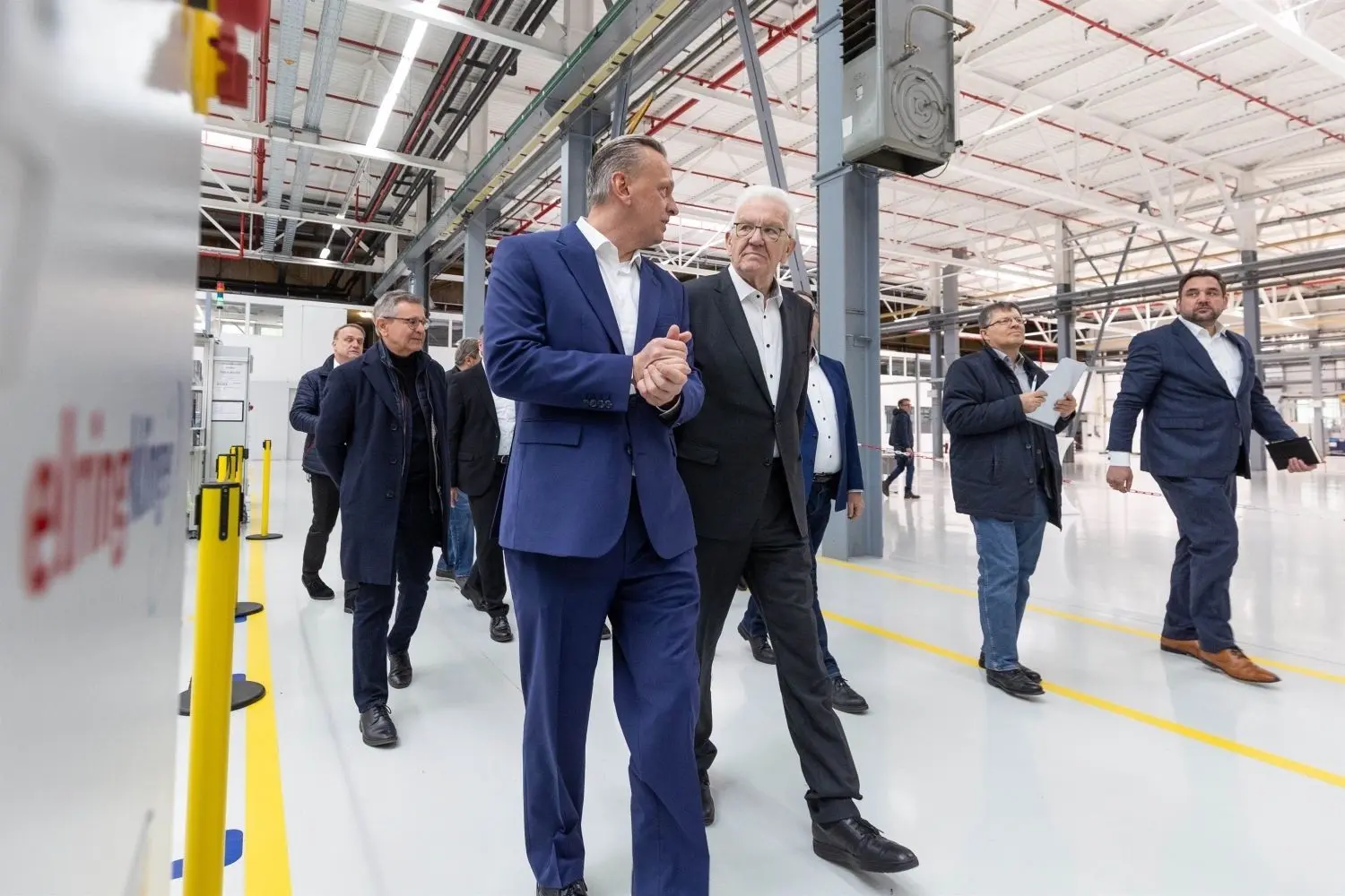 Thomas Jessulat, links, Vorstandsvorsitzender von Elring-Klinger, führt Ministerpräsident Kretschmann durch die Batteriefabrik.