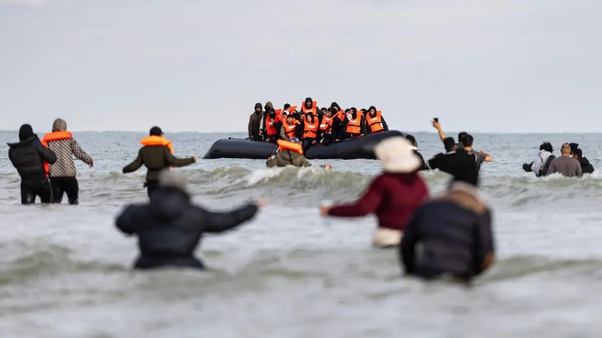 Flüchtlinge versuchen an der französischen Kanalküste, ein Schmugglerboot Richtung Großbritannien zu erreichen. Wegen der drohenden Abschiebung wollen zurzeit viele von dort weiter nach Irland reisen.
Migrants wave to a smuggler's boat in an attempt to cross the English Channel, on the beach of Gravelines, near Dunkirk, northern France on April 26, 2024. Five migrants, including a seven-year-old girl, died on April 23, 2024 trying to cross the Channel from France to Britain, local authorities said, just hours after Britain passed a controversial bill to deport asylum seekers to Rwanda. (Photo by Sameer Al-DOUMY / AFP)