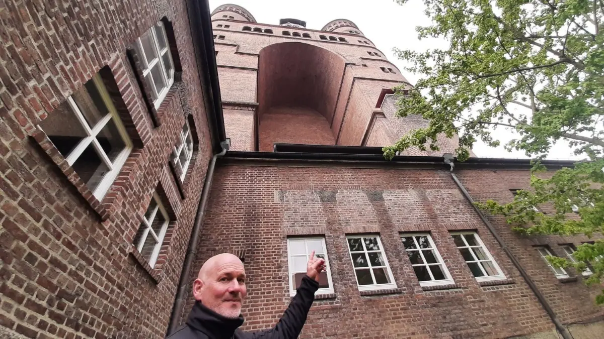 Pauluskirche Ulm: Pfarrer Peter Heiter deutet auf die Ostfassade, wo der Klinker an den Simsen und Brüstungen bröckelt.
