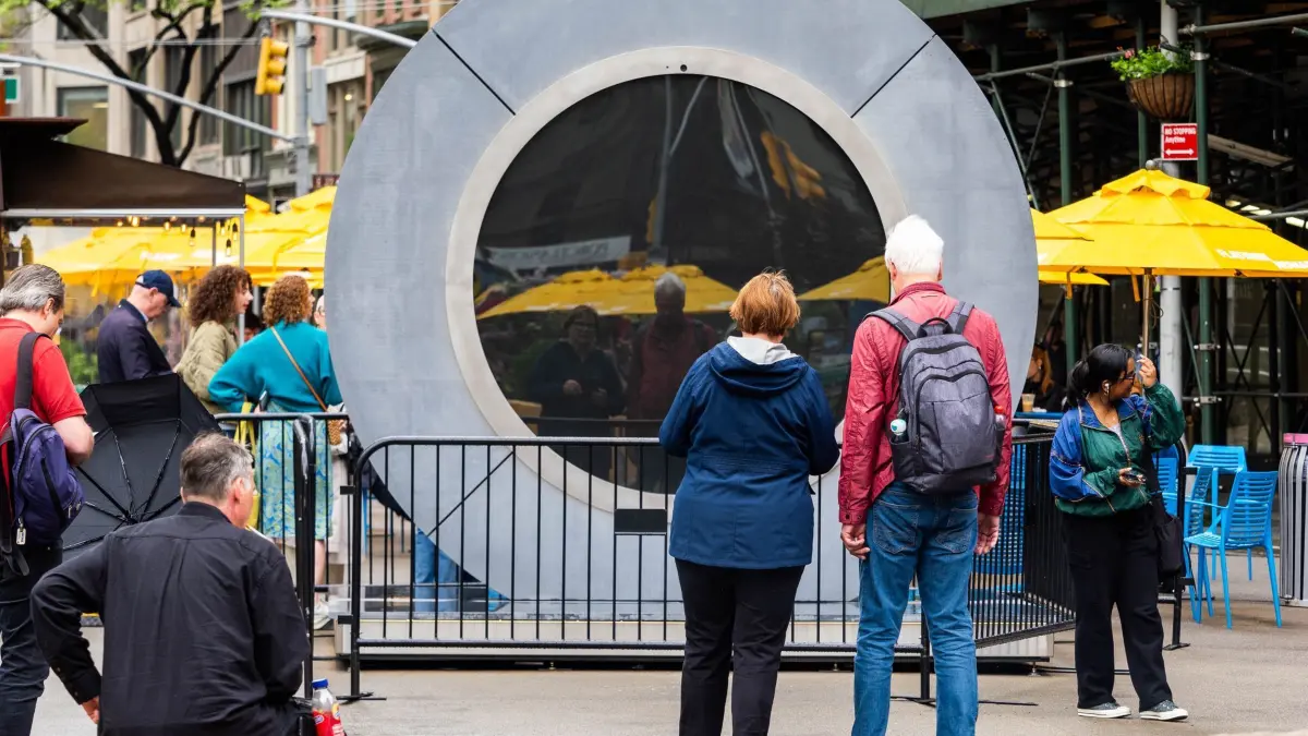 Livestream–Portal zwischen Dublin–New York: 15.05.2024, USA, New York: Touristen sehen auf ihr Spiegelbild statt auf Dublin. Das Live-Video, das Menschen aus NYC und Dublin miteinander verbindet, wurde wegen unangemessenen Verhaltens vorübergehend unterbrochen. Zu den Gründen gehörten blinkende Personen und unangemessene Bilder. Das im Mai 2024 eingeweihte NYC-Portal steht stolz auf der ikonischen Flatiron Plaza und ist im pulsierenden Herzen Manhattans verankert. Als drittes Portal in einem globalen Netzwerk identischer Skulpturen dient es als Leuchtfeuer der Verbindung. An öffentlichen Plätzen aufgestellt, bieten die Portale rund um die Uhr einen ungefilterten Live-Stream, der die Verbindung zwischen Menschen verschiedener Kulturen fördert und Grenzen und Unterschiede überwindet. Foto: Carlos Chiossone/ZUMA Press Wire/dpa +++ dpa-Bildfunk +++