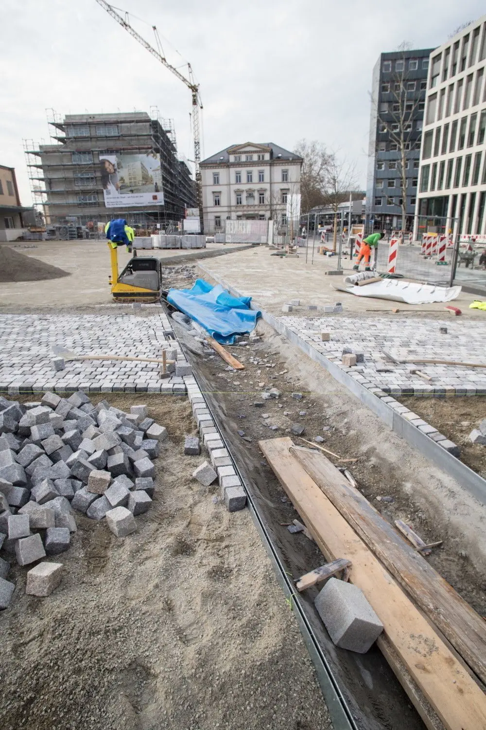 Die Arbeiten am Bahnhofsplatz laufen wieder (linkes Bild).  Das „Stadtsofa“ kommt nun doch im Holzausführung. Im November saß OB Guido Till auf dem Musterstück Probe (rechtes Bild). ⇥Fotos: Staufenpresss/Woletz
