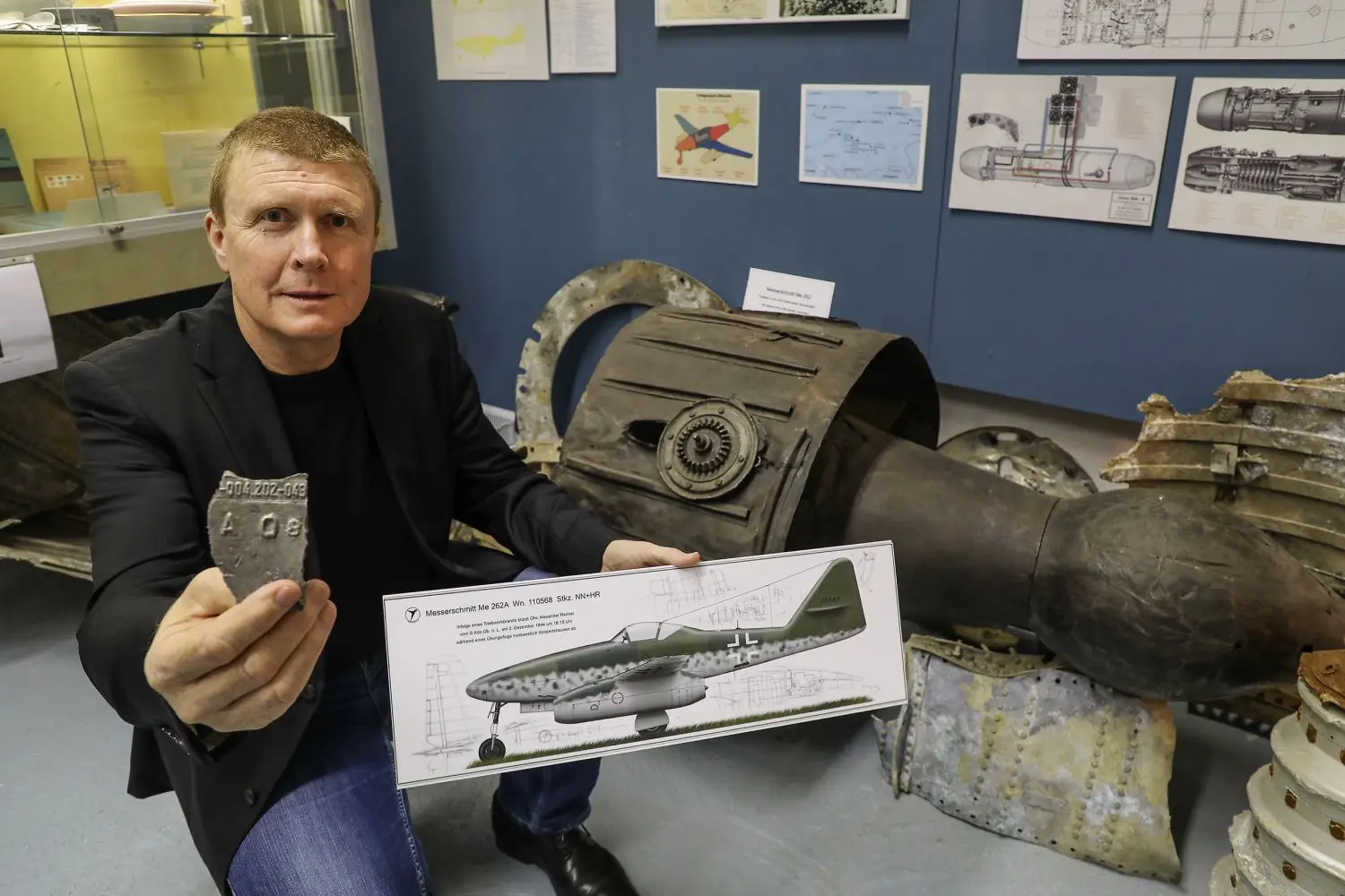 „-004.202-043“ steht auf dem Stück Triebwerksgehäuse, das Siegfried Neidlein in die Kamera hält. Dank dieses Fundstückes konnte die Messerschmitt Me 262, mit der Alexander Reimer bei Wolpertshausen abgestürzt ist, identifiziert werden. Die Flugzeugskizze zeigt, wie die Me 262 wahrscheinlich ausgesehen hat. ⇥