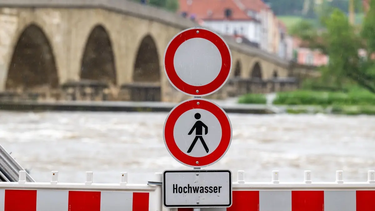 Wetter in Bayern — Hochwasser: 01.06.2024, Bayern, Regensburg: Ein Schild warnt an der Steinernen Brücke vor dem Hochwasser der Donau. Nach den ergiebigen Regenfällen der letzten Tage wird Hochwasser erwartet. Foto: Armin Weigel/dpa +++ dpa-Bildfunk +++