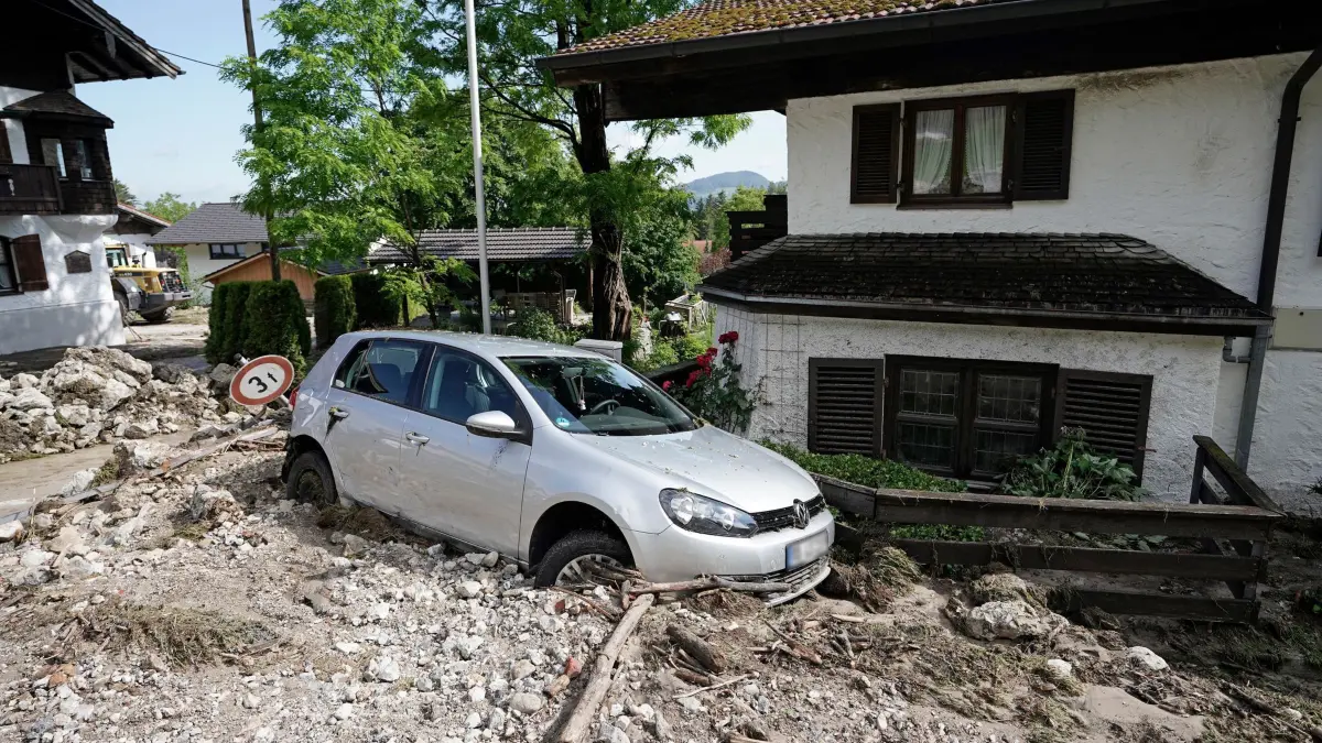 Hochwasser in Bayern — Flintsbach: 04.06.2024, Bayern, Flintsbach: Ein von einer Schlammlawine zerstörter Pkw steht vor einem Haus im Landkreis Rosenheim. In Bayern herrscht nach heftigen Regenfällen vielerorts weiter Land unter. Zehntausende Helfer sind seit Tagen im Einsatz. Foto: Uwe Lein/dpa - ACHTUNG: Kennzeichen wurde(n) aus rechtlichen Gründen gepixelt +++ dpa-Bildfunk +++