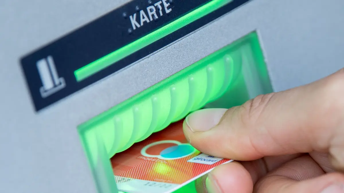 EC–Karte am Automaten: ARCHIV - 30.05.2018, Berlin: ILLUSTRATION - Eine Bankkundin steckt ihre Girokarte in einen Geldautomaten. Durch manipulierte Tankautomaten sollen zwei Männer an Daten von Zahlungs- und Tankkarten gekommen sein und anschließend Kartendoubletten erstellt haben. Die Ermittler gehen von einem Schaden von mehr als 250 000 Euro aus. (zu dpa: «Mehr als 250 000 Euro Schaden durch Tanksäulen-Betrug - Festnahmen») Foto: Fabian Sommer/dpa +++ dpa-Bildfunk +++