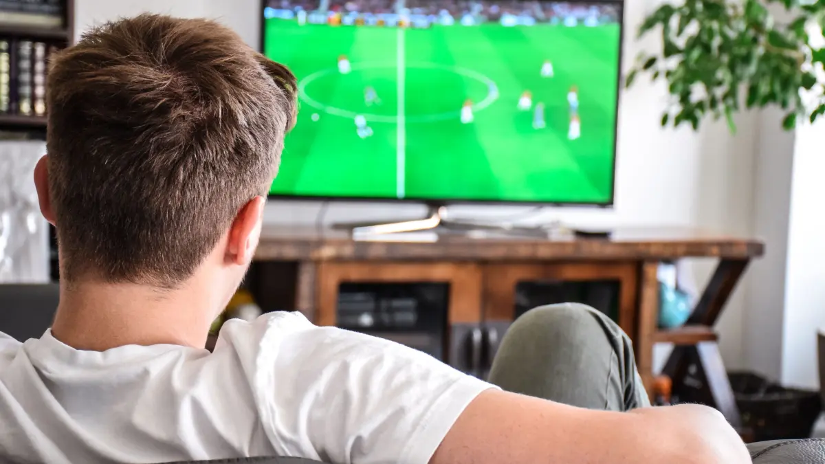 437619207 - Fußball, Fußballspiel, Fernseher, junger Mann, Couch. Download am 10.06.2024 für Caroline Strang, SWP, Wirtschaft, Online+Print. Foto: © Julia/adobe.stock.com