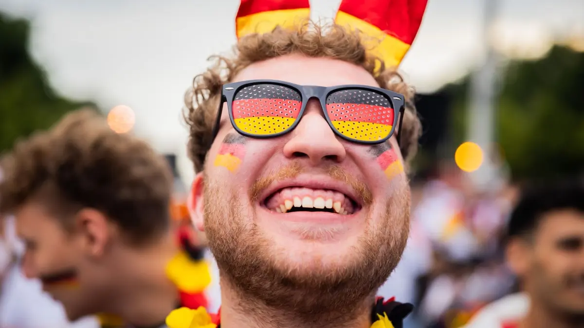 Euro 2024: Public Viewing Berlin: 14.06.2024, Berlin: Fußball, UEFA Euro 2024, Deutschland – Schottland, Vorrunde, Gruppe A, 1. Spieltag: Ein Deutschland-Fan lacht beim Public Viewing in der Fanzone am Brandenburger Tor vor Beginn des Eröffnungsspiels der Fußball-EM. Foto: Christoph Soeder/dpa +++ dpa-Bildfunk +++