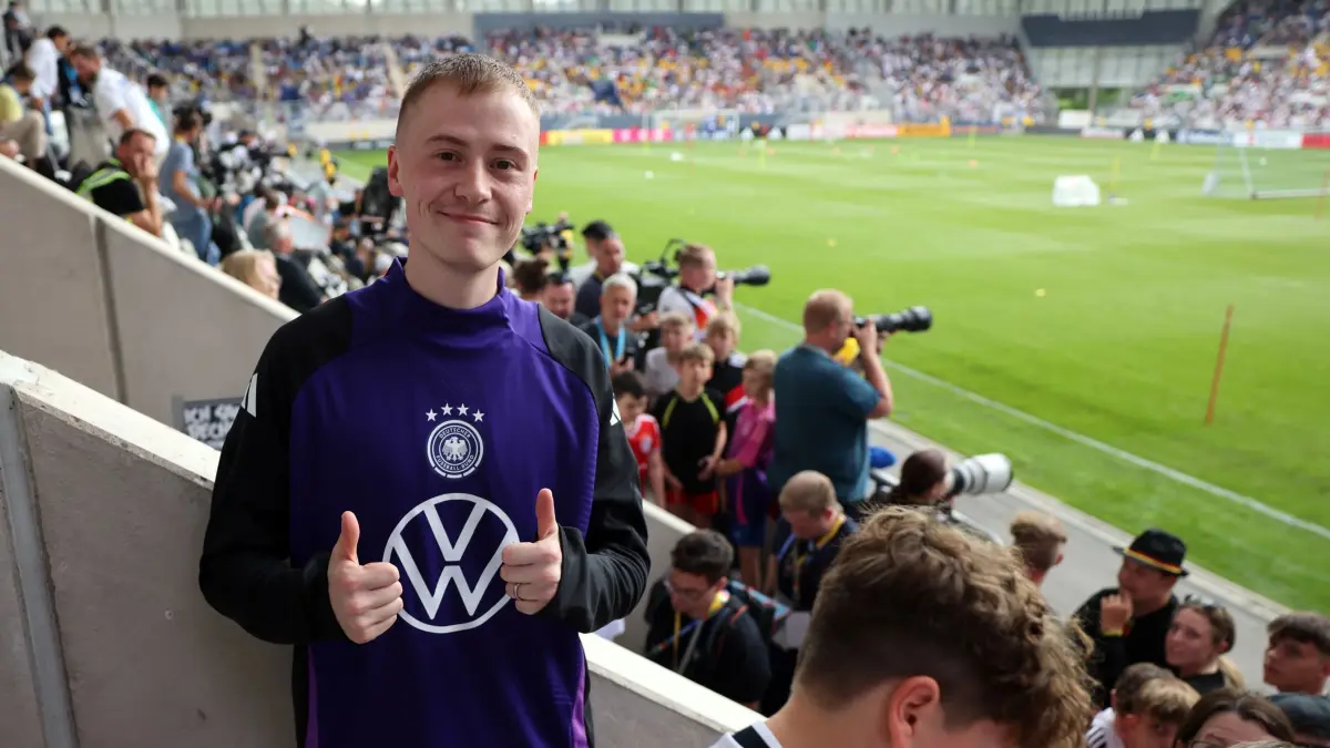 Marvin Wildhage: ARCHIV - 27.05.2024, Thüringen, Jena: Fußball: Nationalmannschaft, Vorbereitung auf die Heim-EM, öffentliches Training der DFB-Auswahl im Ernst-Abbe-Sportfeld. Youtuber Marvin Wildhage steht während des öffentlichen Trainings in Jena auf der Tribüne. Der junge Mann hatte sich im offiziellen Trainings-Outfit samt Kameramann im Deutschland-Trikot zu den Spielern auf den Platz gesellt. Er wurde nach seiner Aktion von einem DFB-Mitarbeiter auf die Ränge begleitet. Eine ähnliche Aktion gelang ihm beim EM-Eröffnungsspiel - mit Konsequenzen. (zu dpa: «Youtuber nach EM-Eröffnung mit Stadionverbot belegt») Foto: Christian Charisius/dpa +++ dpa-Bildfunk +++