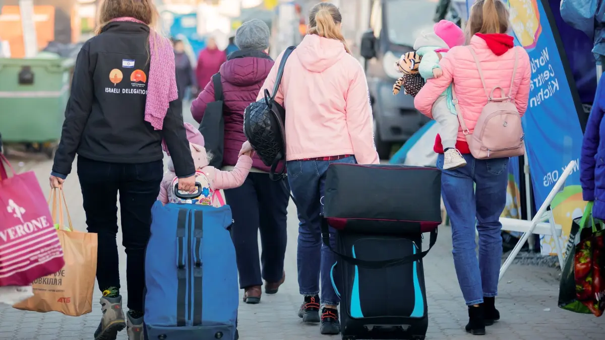 Geflüchtete Frauen und Mädchen: ARCHIV - 13.04.2022, Polen, Przemysl: Frauen und Kinder, die aus der Ukraine geflohen sind, werden im Februar 2022 am Grenzübergang Medyka, kurz hinter der ukrainischen Grenze, auf polnischer Seite, von einer freiwilligen Helferin (l) begleitet.Seit Kriegsausbruch hat sich laut einer Studie die Einstellung der Polen zu den aufgenommenen Flüchtlingen verschlechtert. (zu dpa: «Umfrage: Haltung der Polen zu Ukraine-Flüchtlingen verschlechtert sich») Foto: Christoph Soeder/dpa +++ dpa-Bildfunk +++