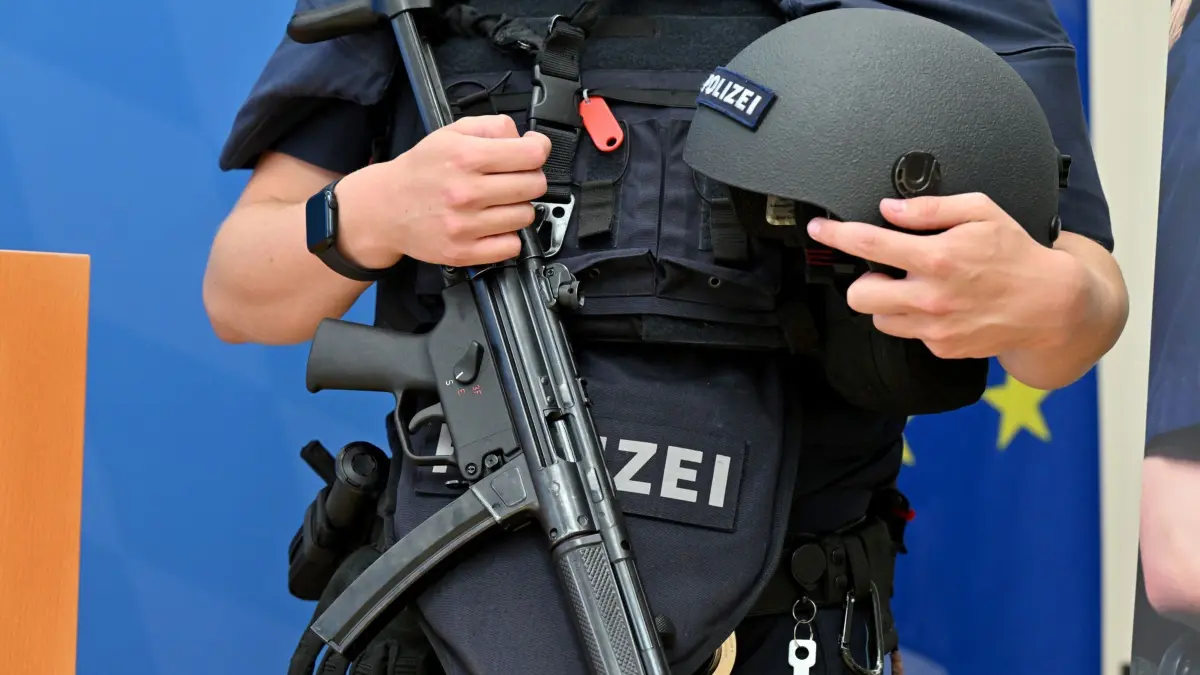 REPORT — Schutzausrüstung Polizei: 24.06.2024, Bayern, München: Ein Polizist trägt während der Pressekonferenz „Landeslagebild 2023 zur Gewalt gegen Polizeibeamte“ im Innenministerium eine Schutzausrüstung zur Präsentation. Das bayernweite Lagebild wurde erstmals 2010 erhoben. 2022 wurden knapp 3 000 Polizistinnen und Polizisten verletzt, darunter 22 schwer. Foto: Peter Kneffel/dpa - ACHTUNG: Seriennummer der Waffe wurde gepixelt +++ dpa-Bildfunk +++