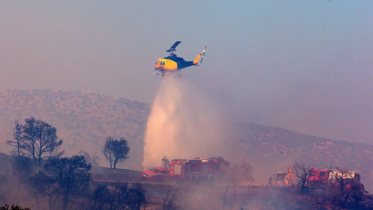Waldbrand in Griechenland: 30.06.2024, Griechenland, Keratea: Ein Feuerwehrhubschrauber wirft Wasser auf einen Waldbrand in Keratea, südöstlich von Athen, Griechenland, ab. Seit dem Beginn der Waldbrandsaison am 1. Mai werden die Feuerwehrleute täglich zu Dutzenden von Waldbränden im ganzen Land gerufen. Foto: Marios Lolos/XinHua/dpa +++ dpa-Bildfunk +++