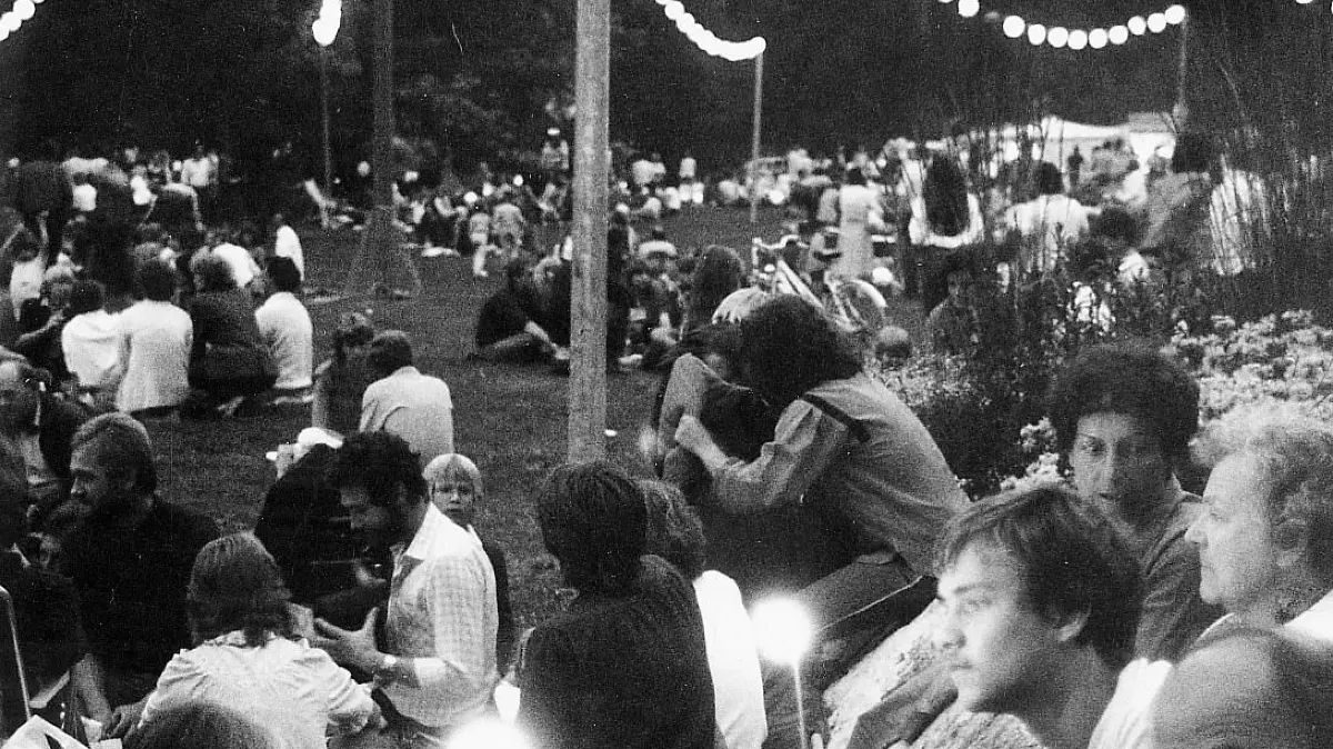 Ulm, Friedrichsau, Schwörmontag 1982: auf den Wiesen in der Friedrichsau sitzen viele Leute, einige zünden Fackeln an, Dämmerung, Lichterketten brennen