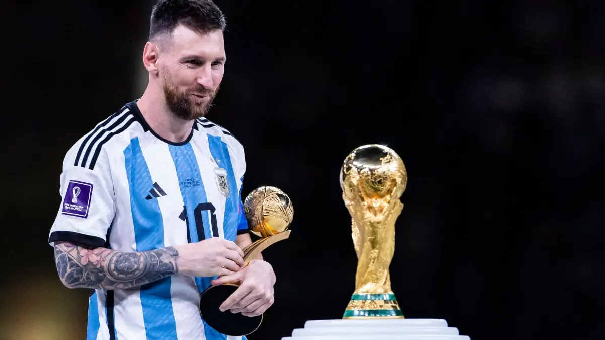 WM 2022 - Argentinien - Frankreich: ARCHIV - 18.12.2022, Katar, Lusail: Fußball: WM, Argentinien - Frankreich, Finalrunde, Finale, Lusail Stadion, Argentiniens Lionel Messi (l) schaut mit der Auszeichnung „adidas Golden Ball Award“ auf den WM - Pokal. (zu dpa: «Tränen, Leiden und doch die nächste Messi-Krönung») Foto: Tom Weller/dpa +++ dpa-Bildfunk +++